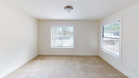 a spacious living room with a large window and carpet