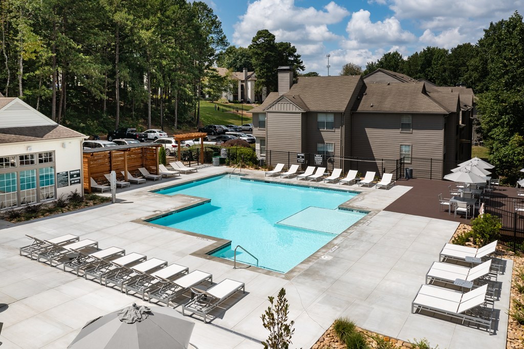 A large swimming pool surrounded by lounge chairs and umbrellas.