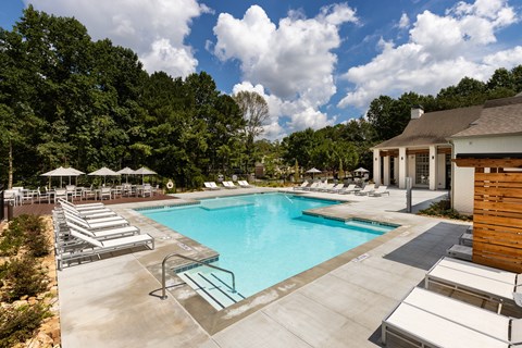 A large swimming pool surrounded by sun loungers and umbrellas.