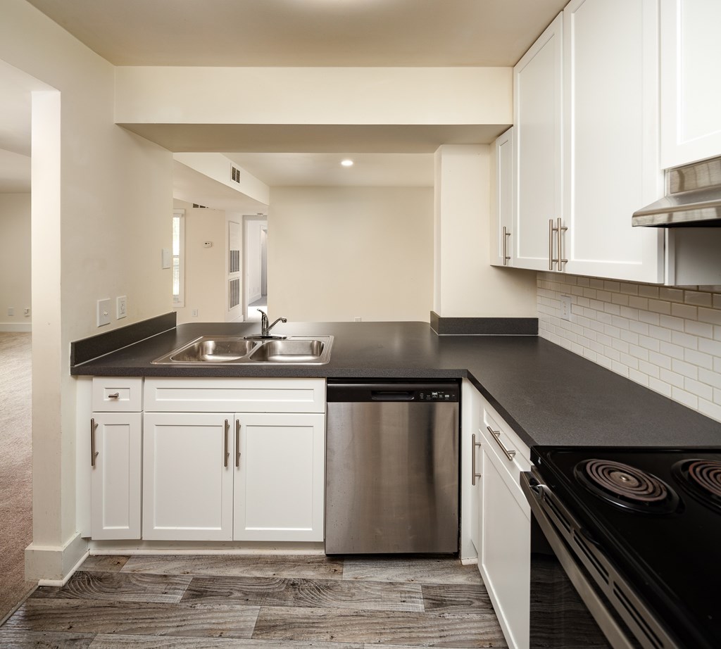 A modern kitchen with white cabinets and black countertops.
