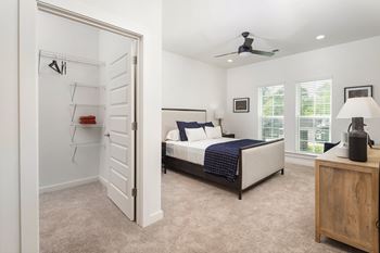 A bedroom with a bed, dresser, and a ceiling fan.