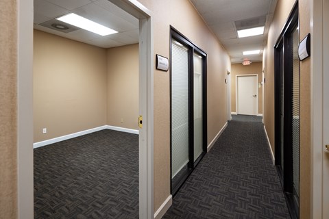 A long hallway with a carpeted floor and doors on both sides.