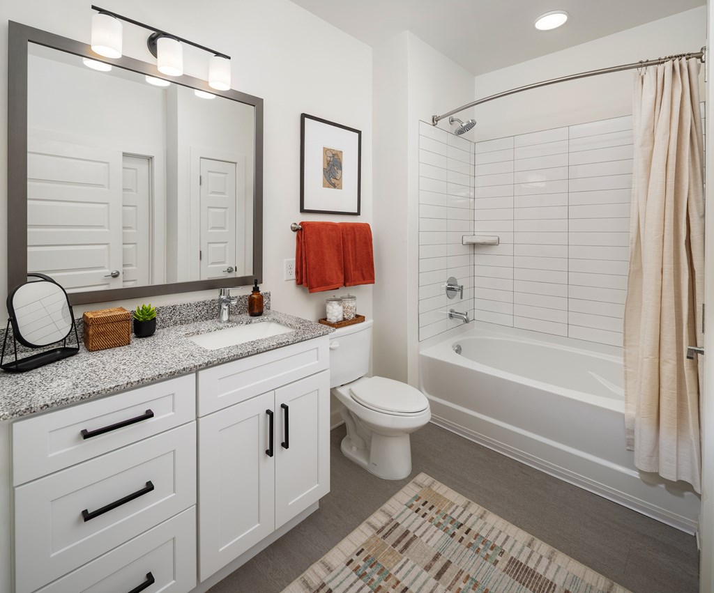 A bathroom with a white toilet, sink, and a shower with a beige shower curtain.