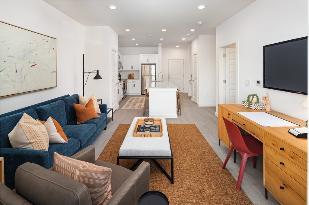 A living room with a blue couch and a brown rug.