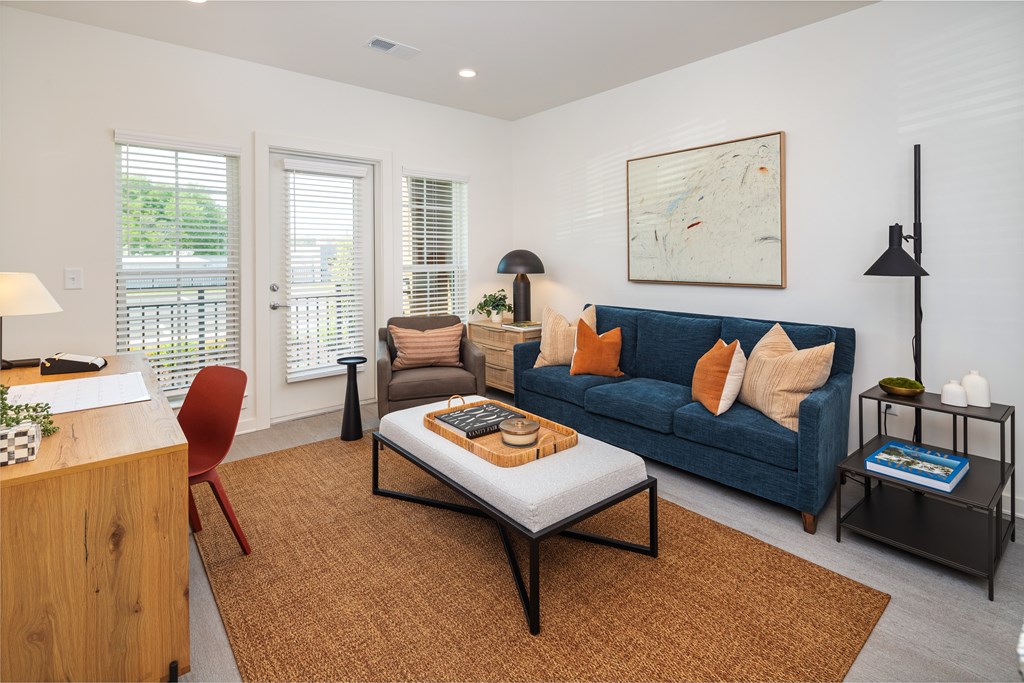 A living room with a blue couch and a brown rug.