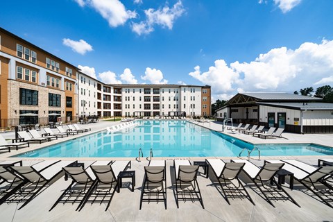 A large swimming pool surrounded by sun loungers and chairs.