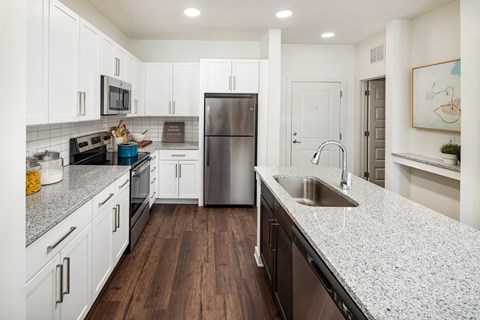 A modern kitchen with white cabinets and a stainless steel refrigerator.