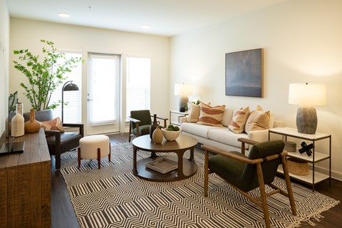 A living room with a black and white patterned rug and a green chair.