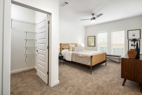 A bedroom with a bed, dresser, and a ceiling fan.