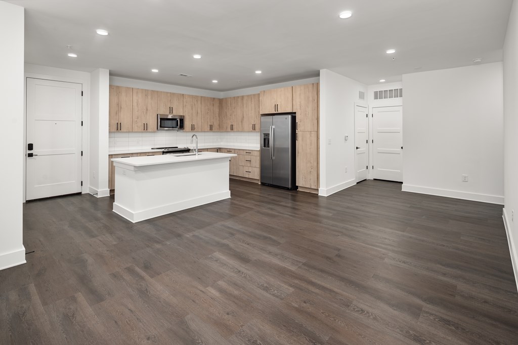 A kitchen with a refrigerator, sink, and cabinets.
