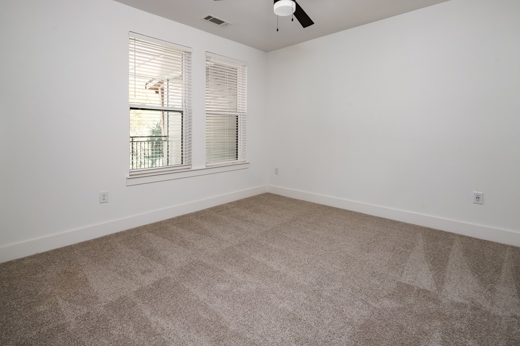 A room with a carpeted floor and a window with blinds.