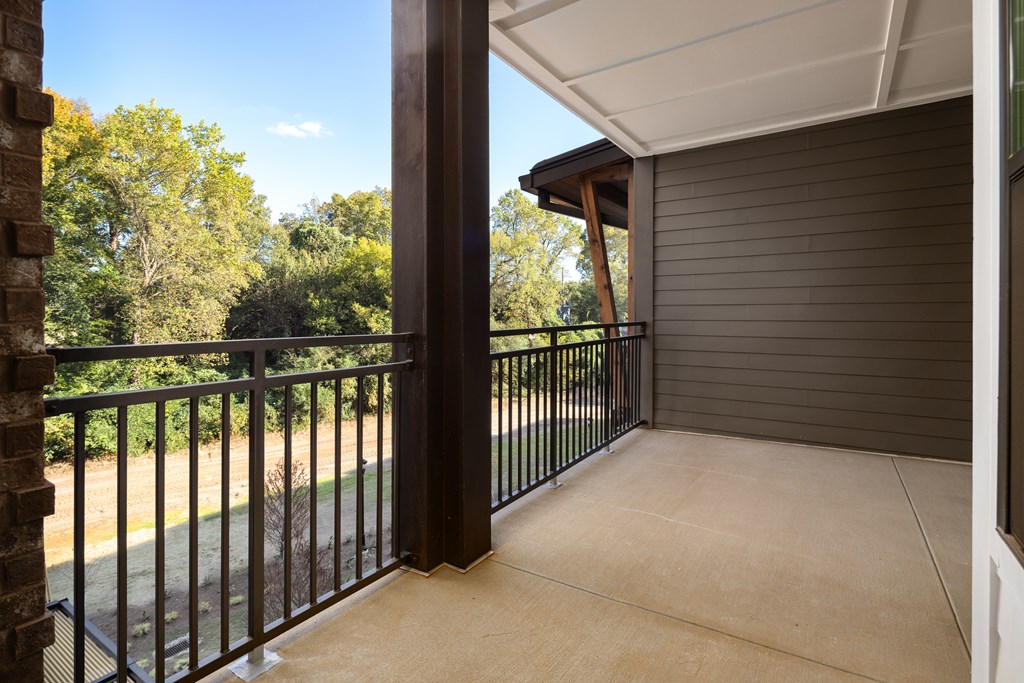 A balcony with a black railing and a view of trees.