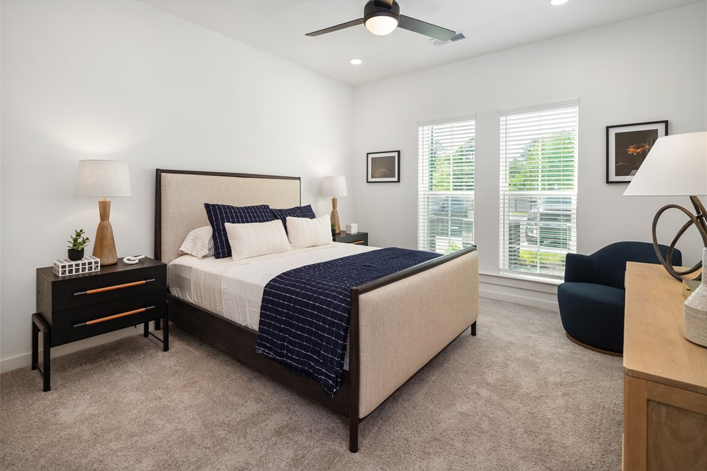 A bedroom with a bed, nightstand, dresser and chair.