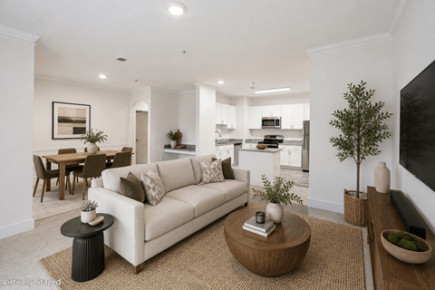 A living room with a white couch, a coffee table, and a dining table.
