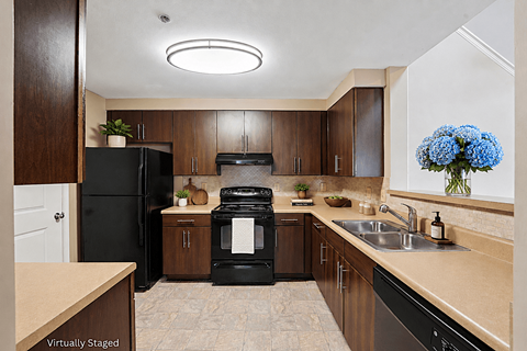 A kitchen with black appliances and wooden cabinets.