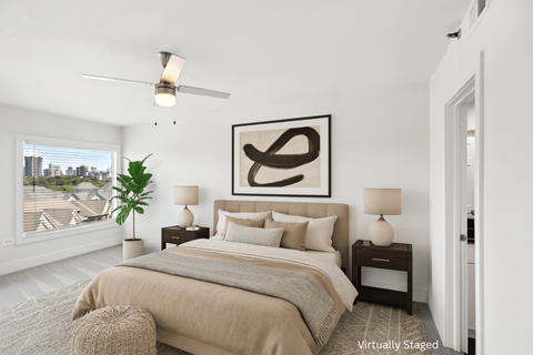 A bedroom with a large bed, a ceiling fan, and a large abstract painting above the bed.