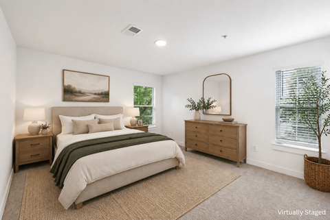 A bedroom with a bed, nightstands, and a plant.