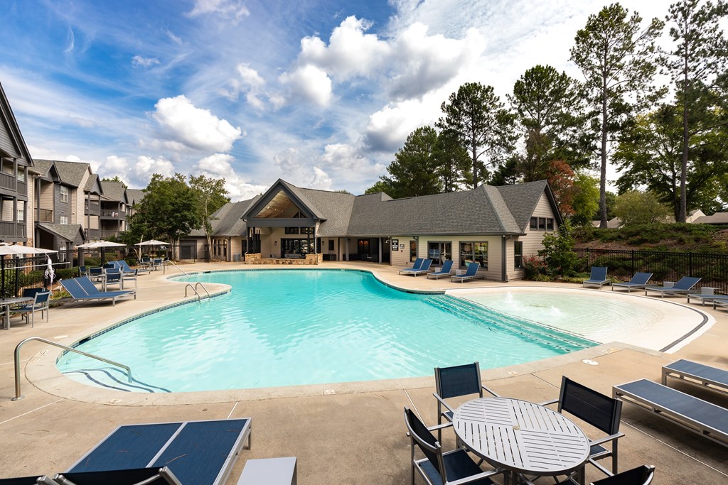 A large outdoor swimming pool surrounded by lounge chairs and umbrellas.