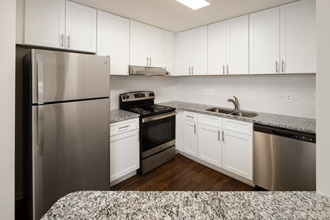 A kitchen with white cabinets and a stainless steel refrigerator.