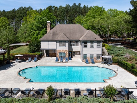 a large pool in front of a house with chairs around it