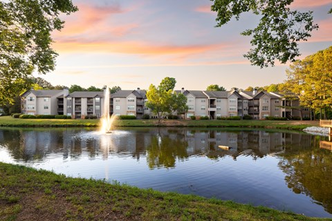 A serene pond surrounded by residential buildings with a fountain in the middle.