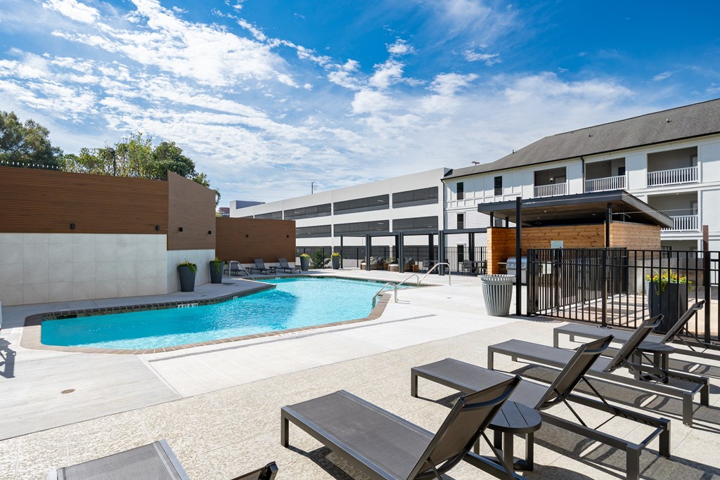 A pool area with sun loungers and a building in the background.
