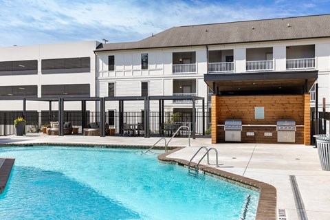 A swimming pool in front of a building with a black fence around it.