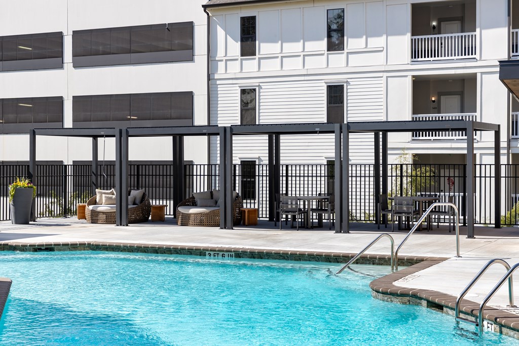 A pool area with a black fence and a white building in the background.