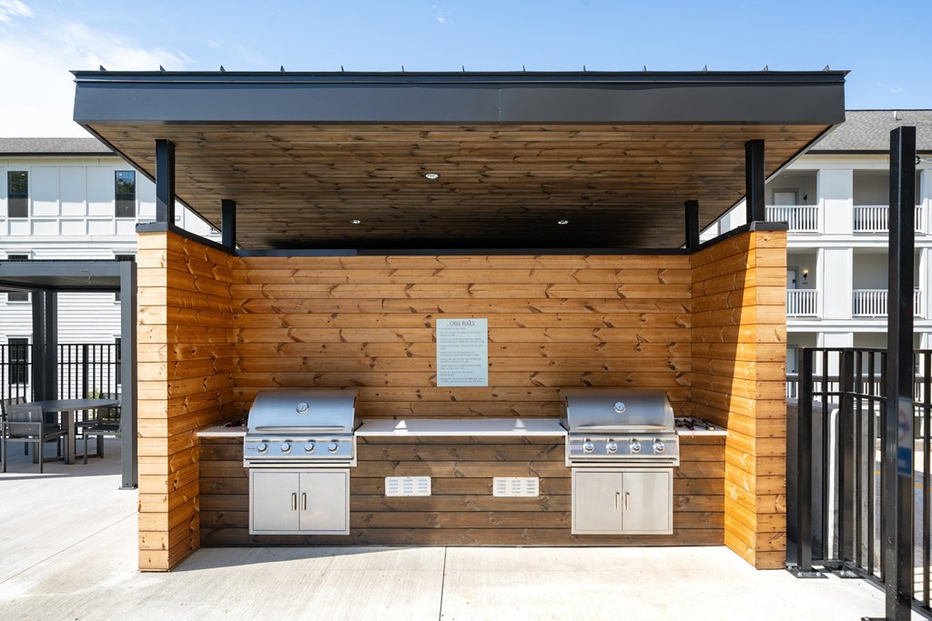 A wooden outdoor kitchen with two grills and a sink.