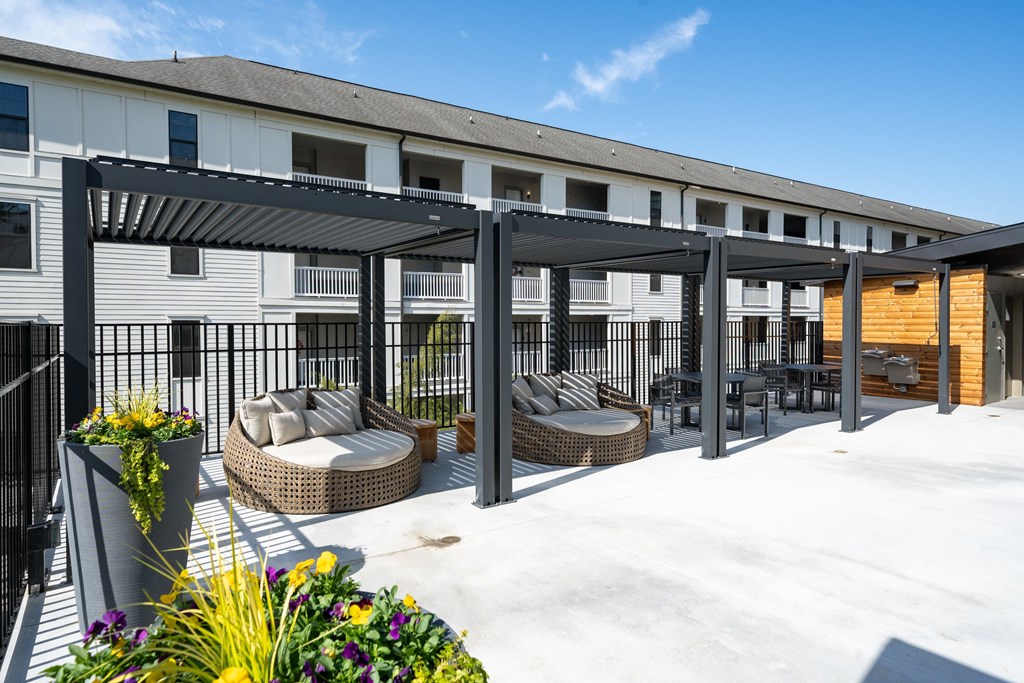 A patio area with a black pergola and wicker furniture.