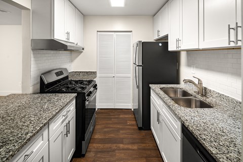 a kitchen with white cabinets and granite counter tops and a black refrigerator