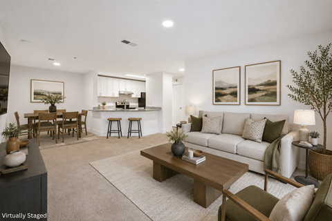 A modern living room with a white couch, wooden coffee table, and a dining table with chairs.