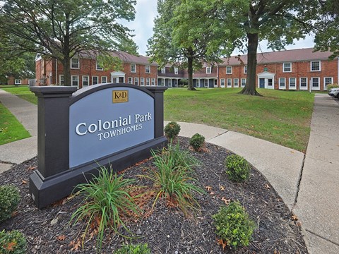 A sign that says Colonial Park Townhomes in front of some buildings.