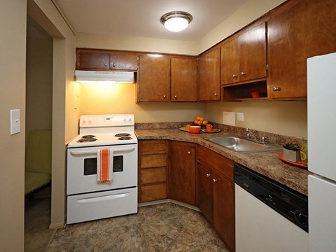A kitchen with a white stove and wooden cabinets.