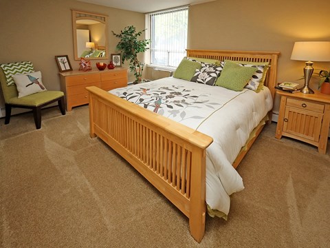 Bedroom with natural wood furniture and green accents at Water's Edge Apartments, Euclid, OH 44123