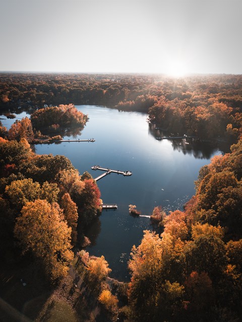 A serene lake surrounded by autumn trees with boats sailing on the water.