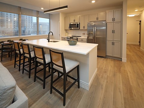 A kitchen with a white counter top and wooden floors.