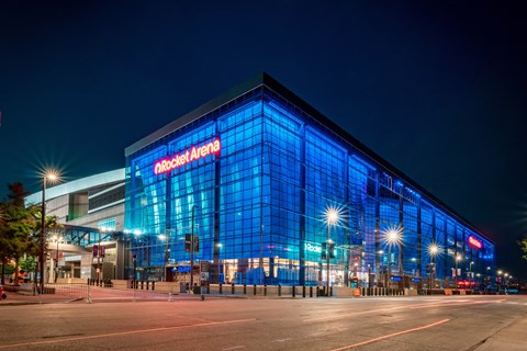 The Rocket Arena is a large, modern building with a glass facade and is lit up at night.