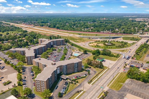 A large building complex is surrounded by a parking lot and a highway.
