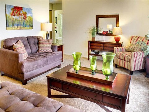 a living room with couches and a table with green vases