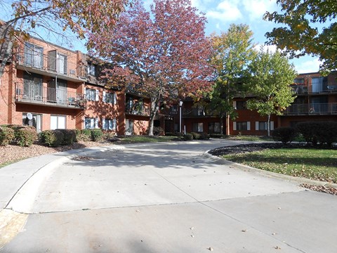 Apartment complex with a tree with red leaves.