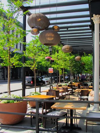 A restaurant with tables and chairs and hanging lamps.