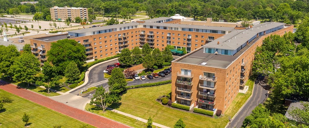 a large brick building with a gray roof and a grassy area in front of it