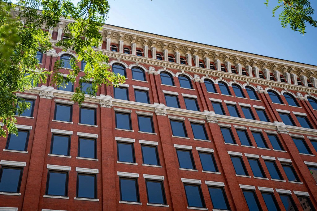 A red brick building with many windows and a tree in front.