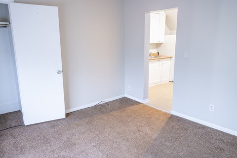 A room with a white door and a carpeted floor.