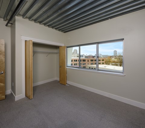 A room with a large window and a view of buildings outside.