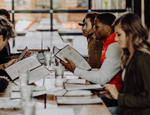 A group of people sitting at a table with menus in front of them.