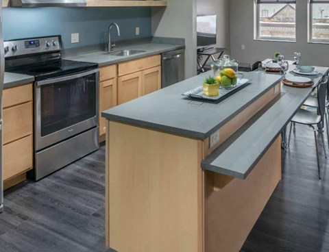 A modern kitchen with a stove, oven, and a dining table set for two.