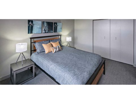 A bedroom with a bed, a nightstand, and a lamp.