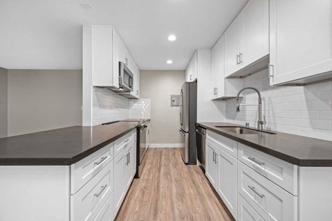 a kitchen with white cabinets and a sink and a refrigerator